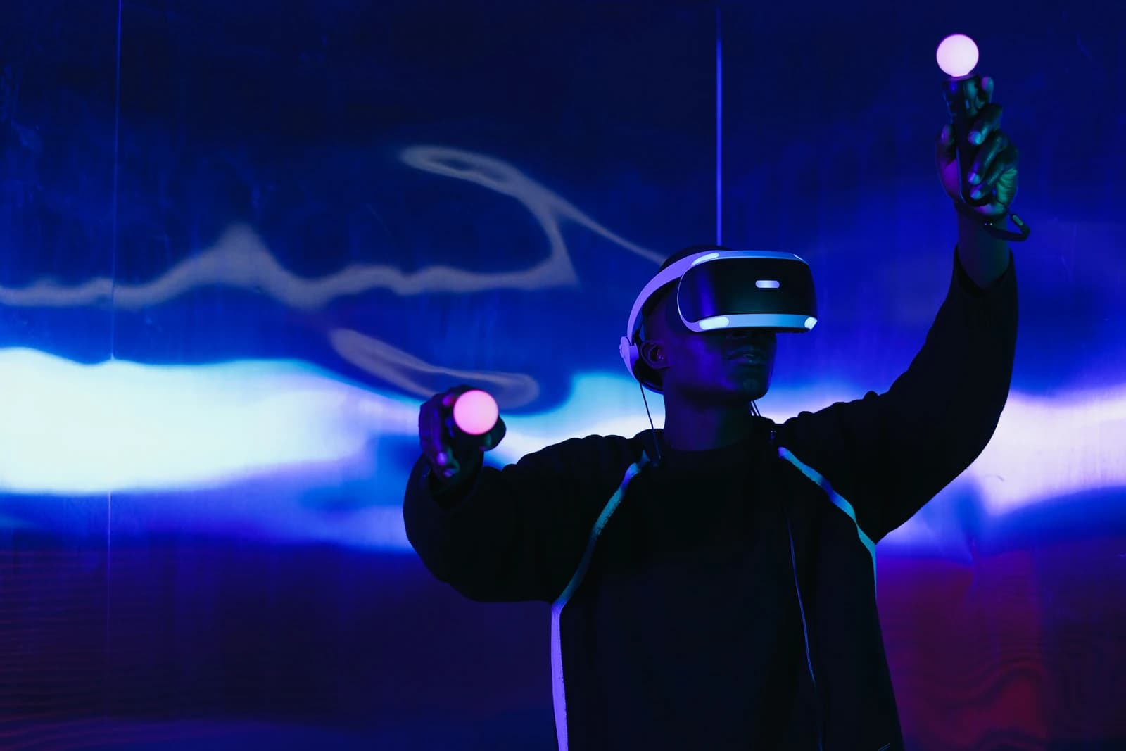A person in a VR headset reaching into a projected scene, a tracked controller lit in each hand